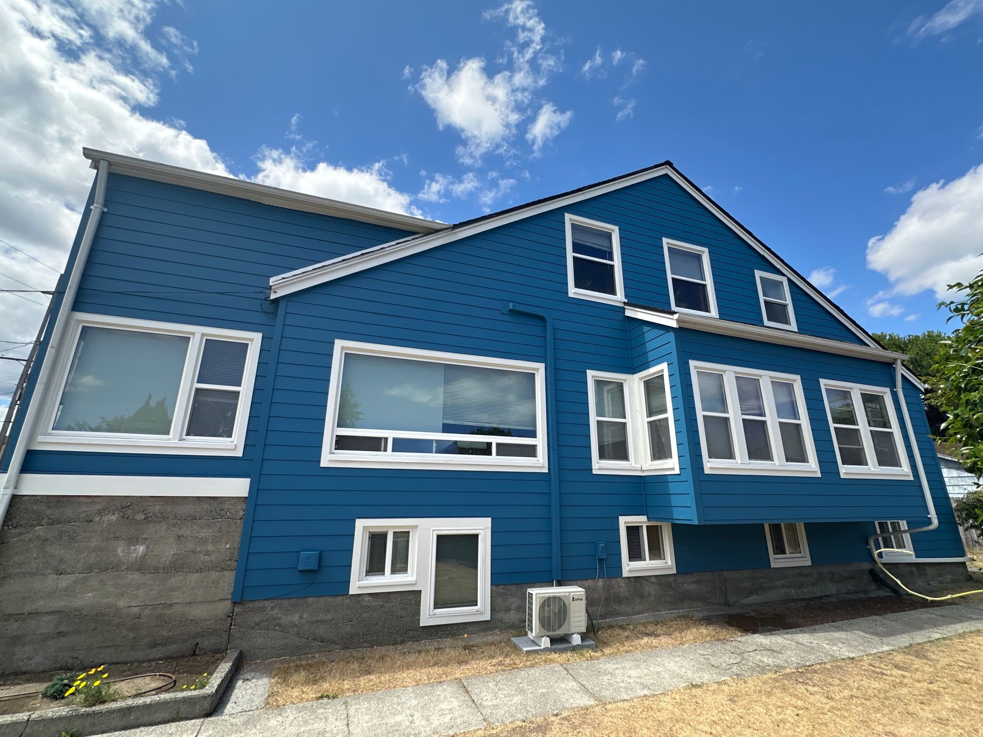 A large blue house with a lot of windows on a sunny day.