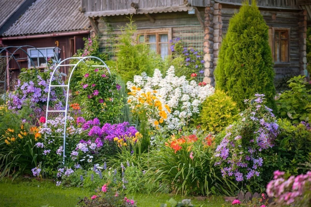 White House with a lush green lawn and staircase adorned with vibrant plants.