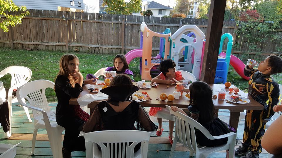 A group of children are sitting at a table with plates of food.
