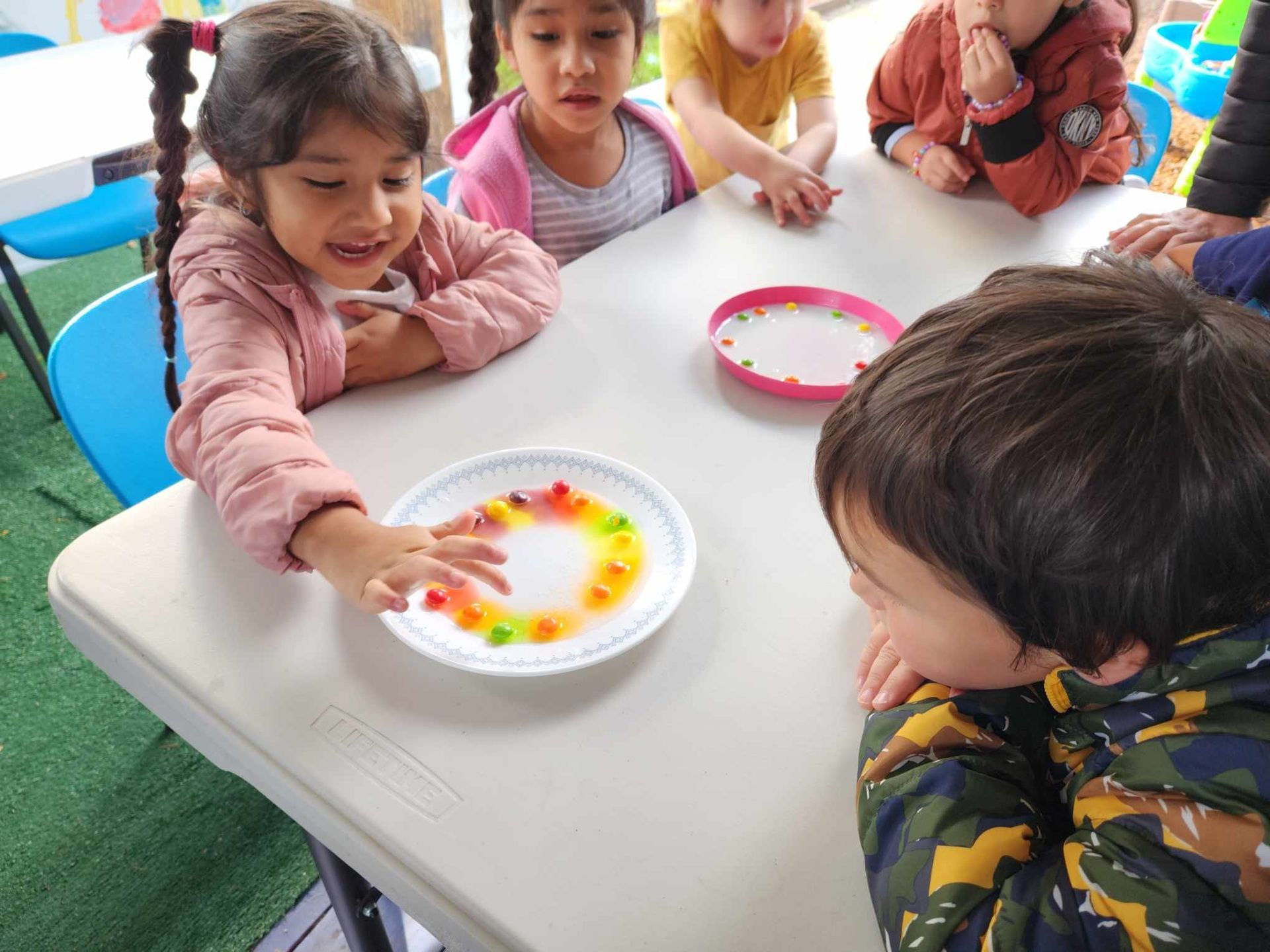 A group of children are sitting at a table playing with gummy bears.