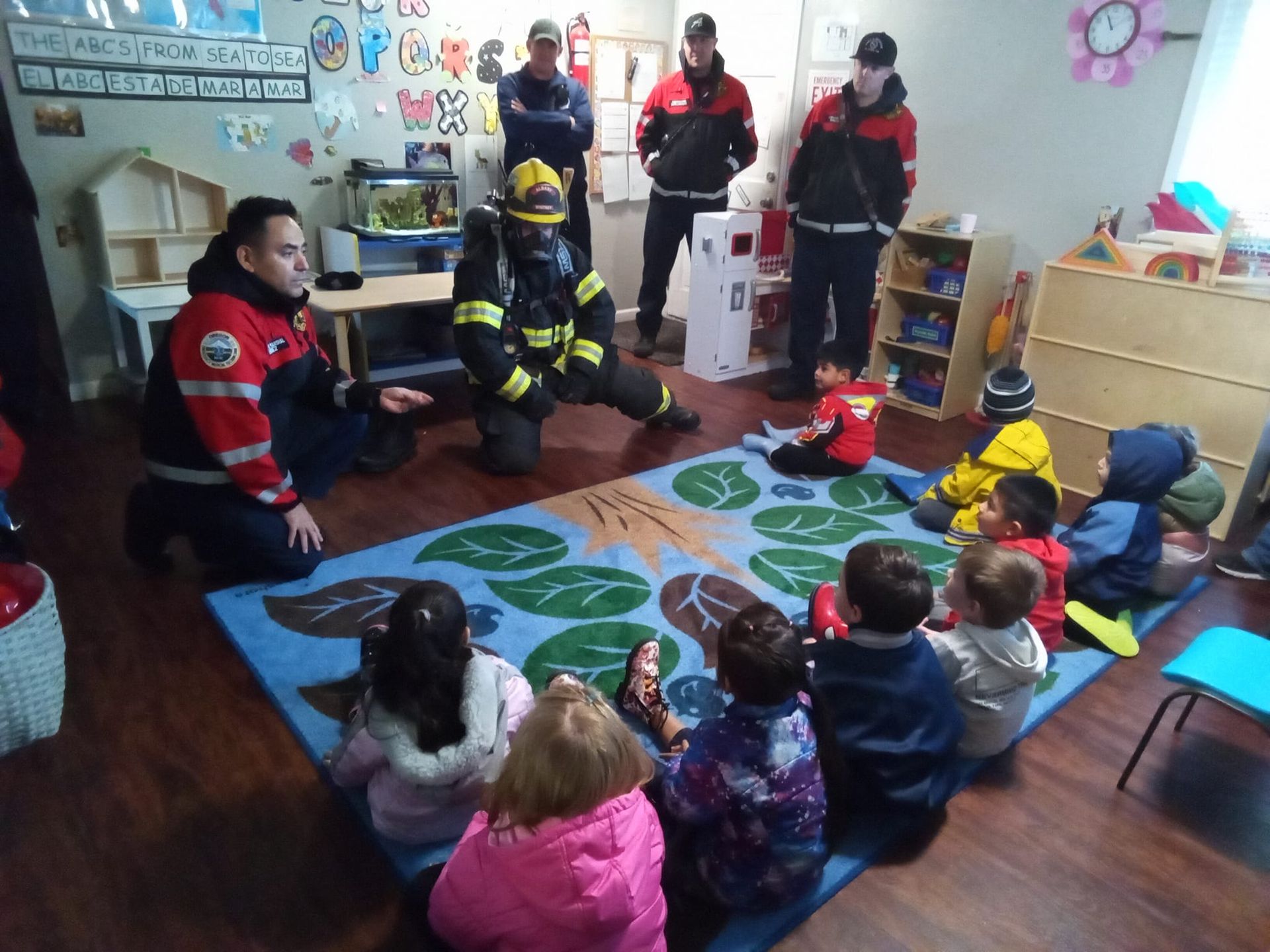A group of firefighters are talking to a group of children