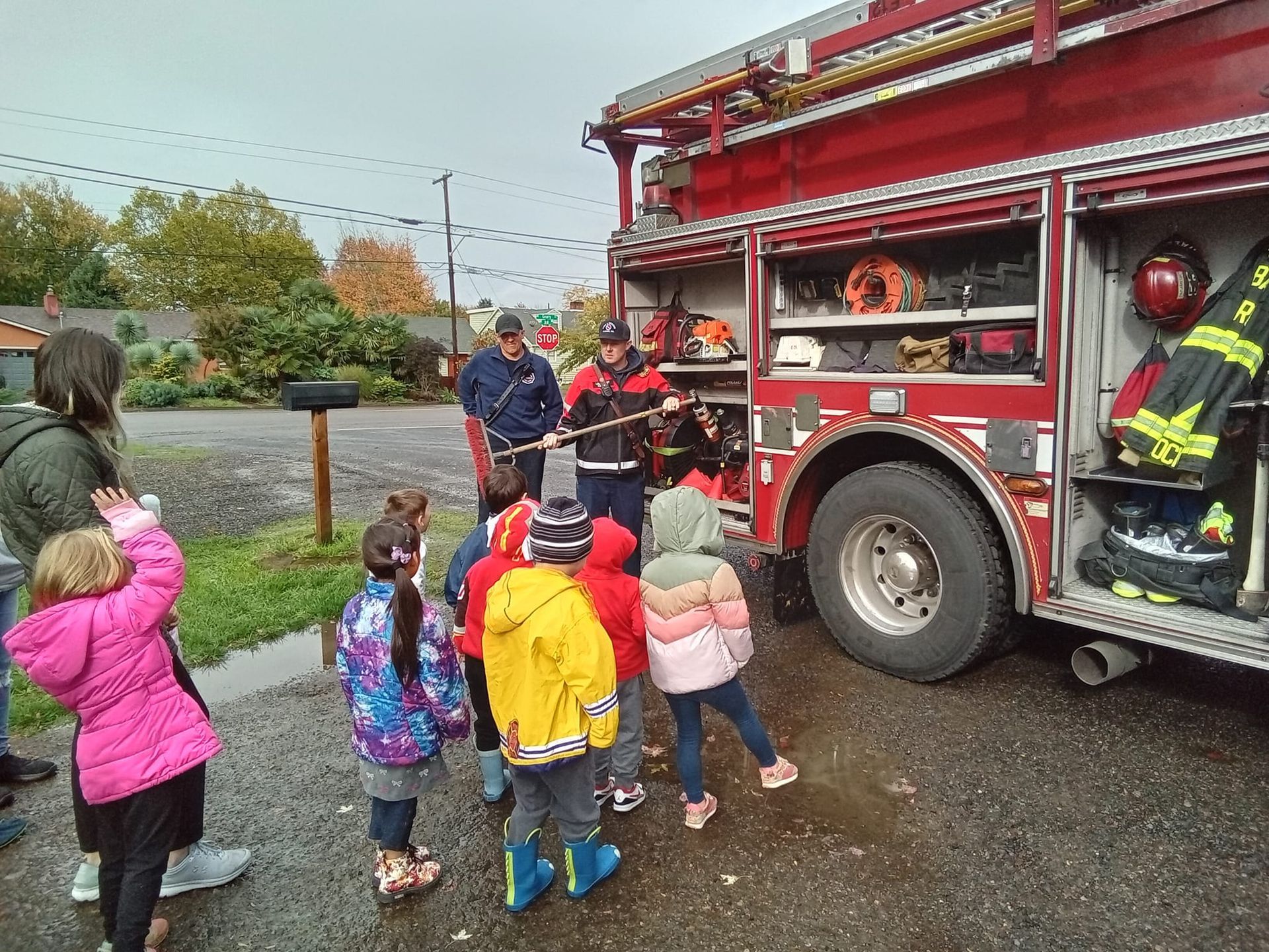 A group of children are standing in front of a fire truck.