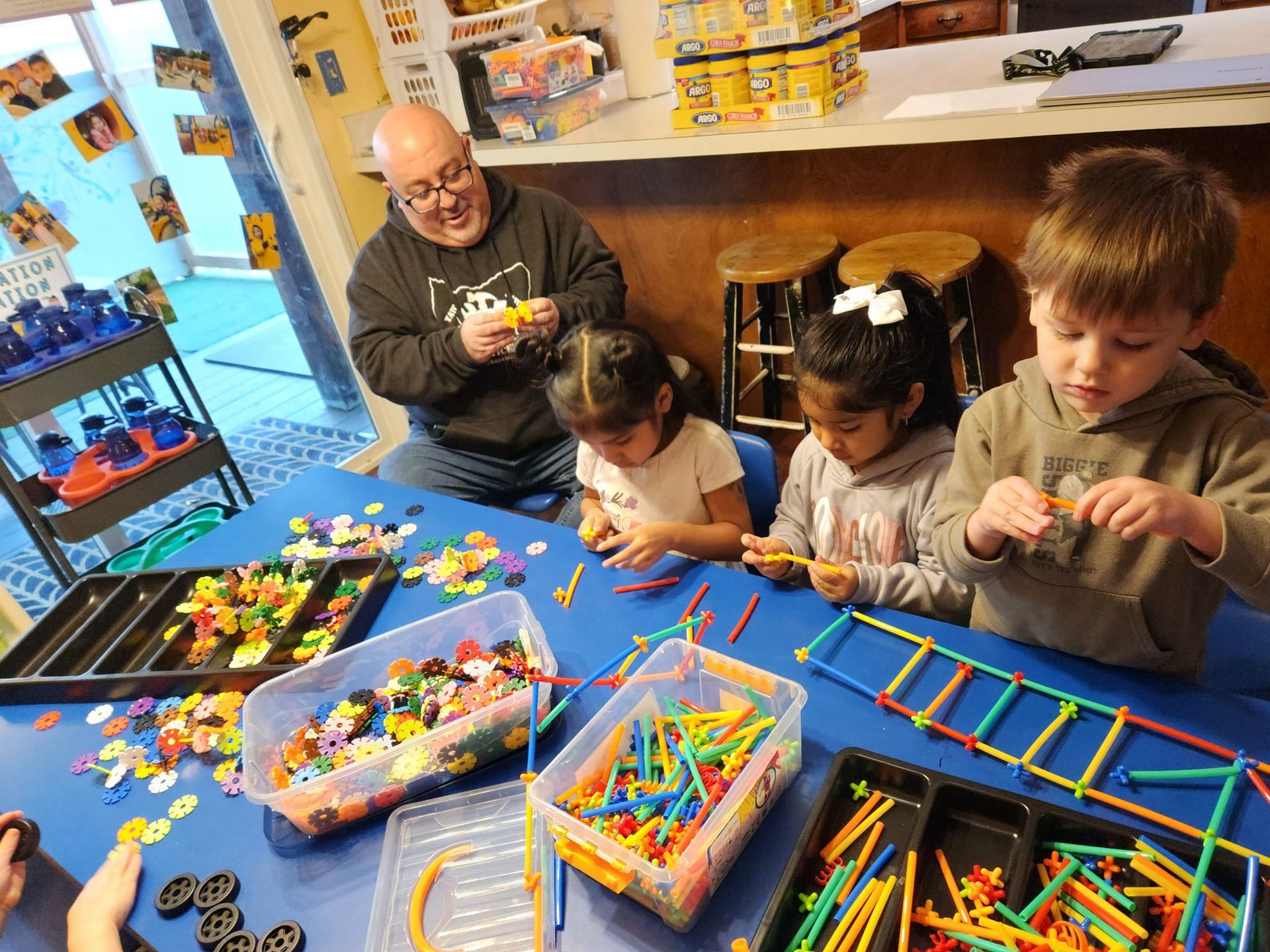 A group of children are sitting at a table playing with toys.