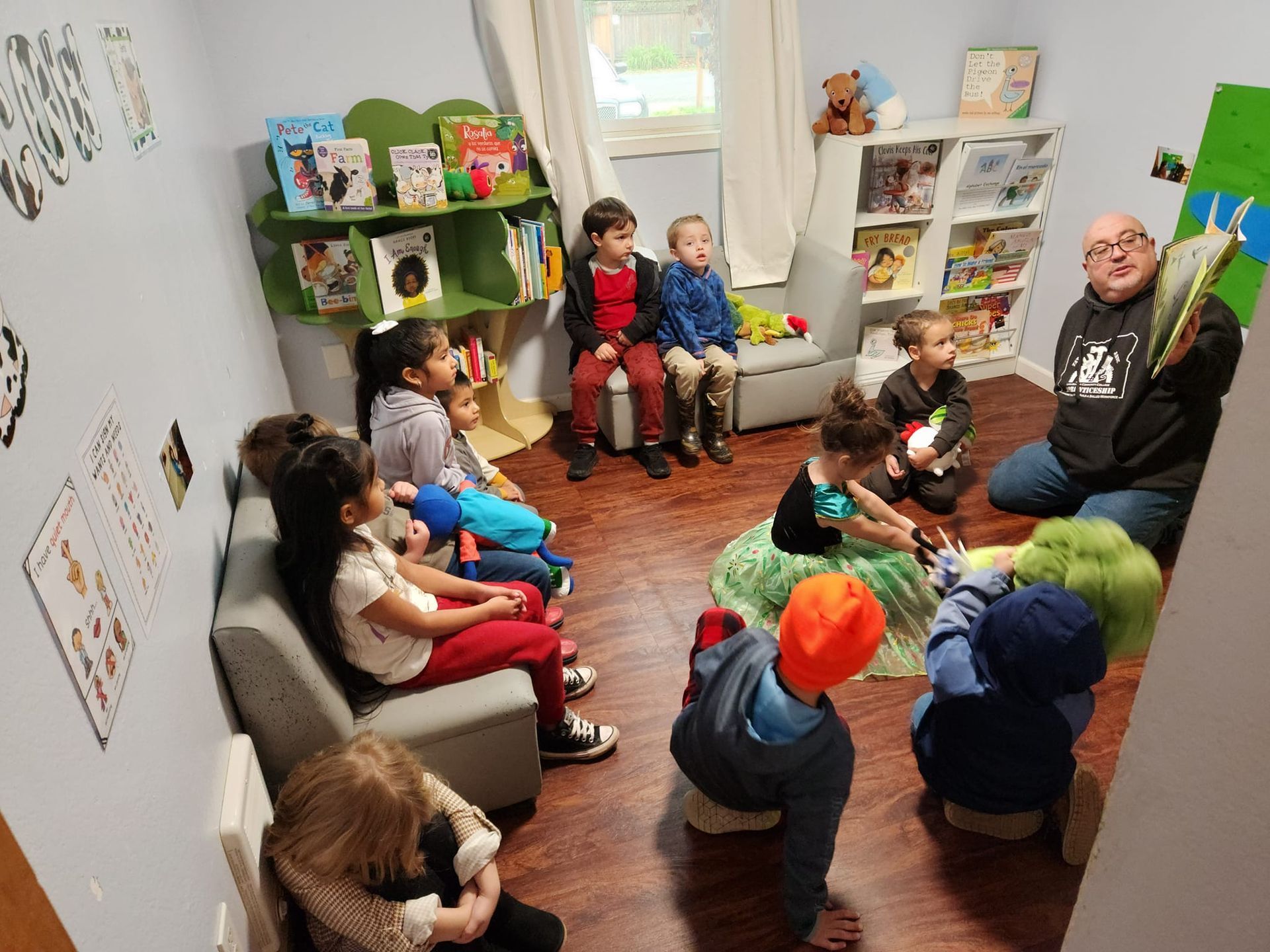 A man is reading a book to a group of children in a room.