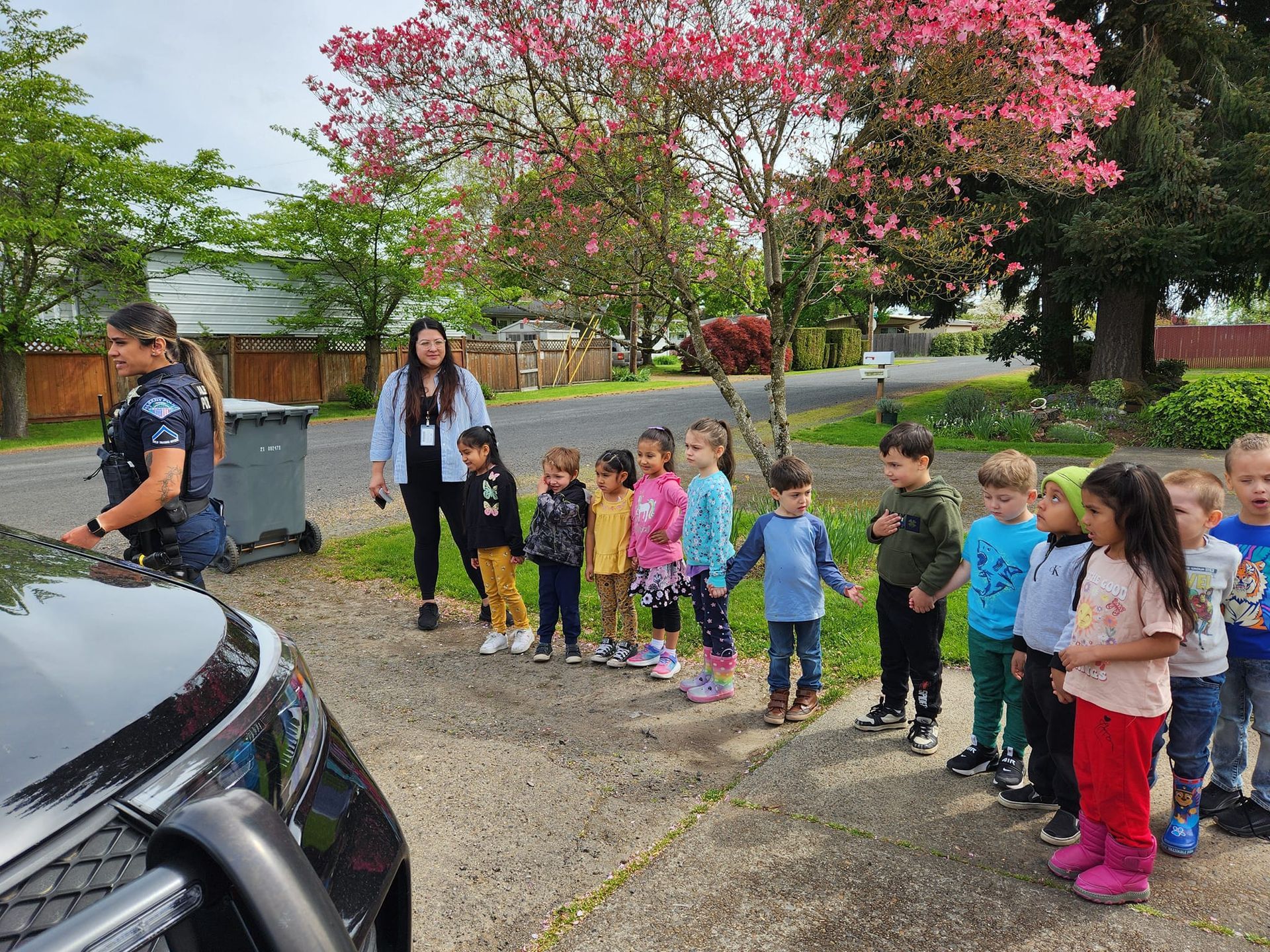 A group of children standing in front of a police car.