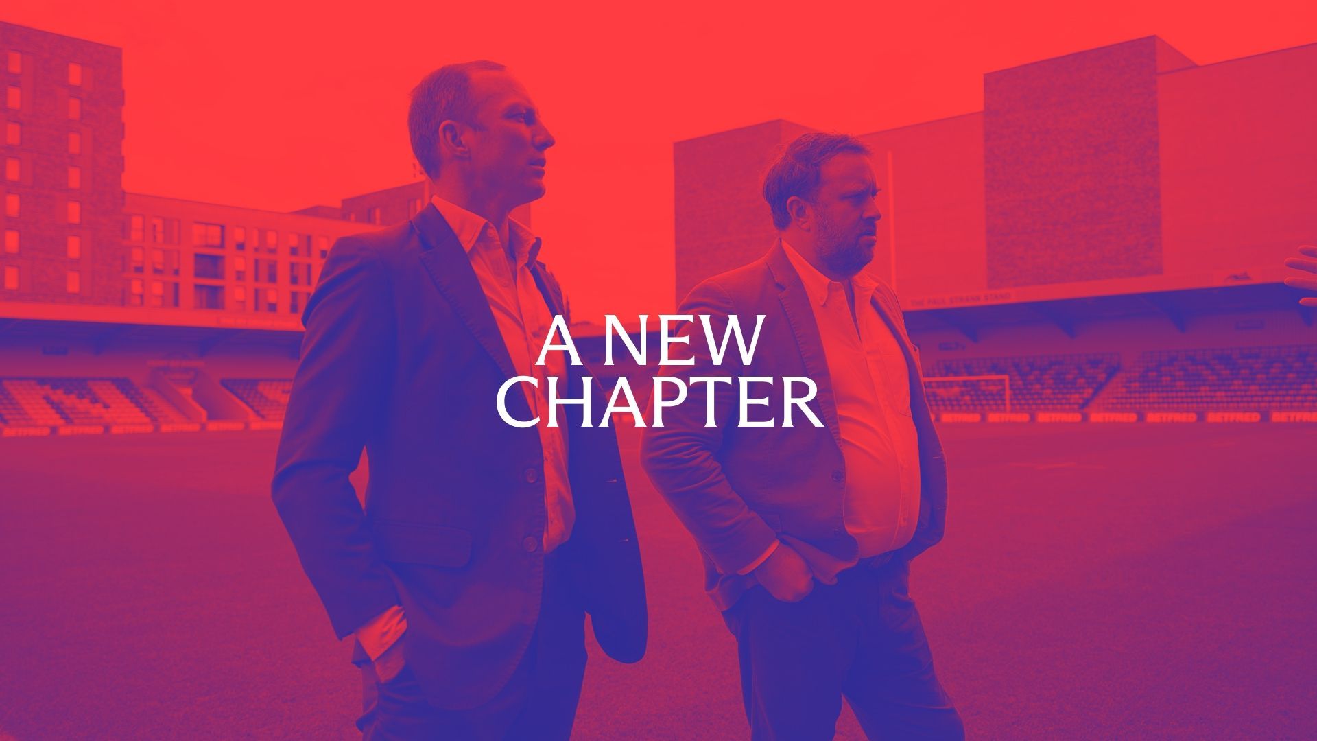 Two men walking on a stadium field, text overlay 