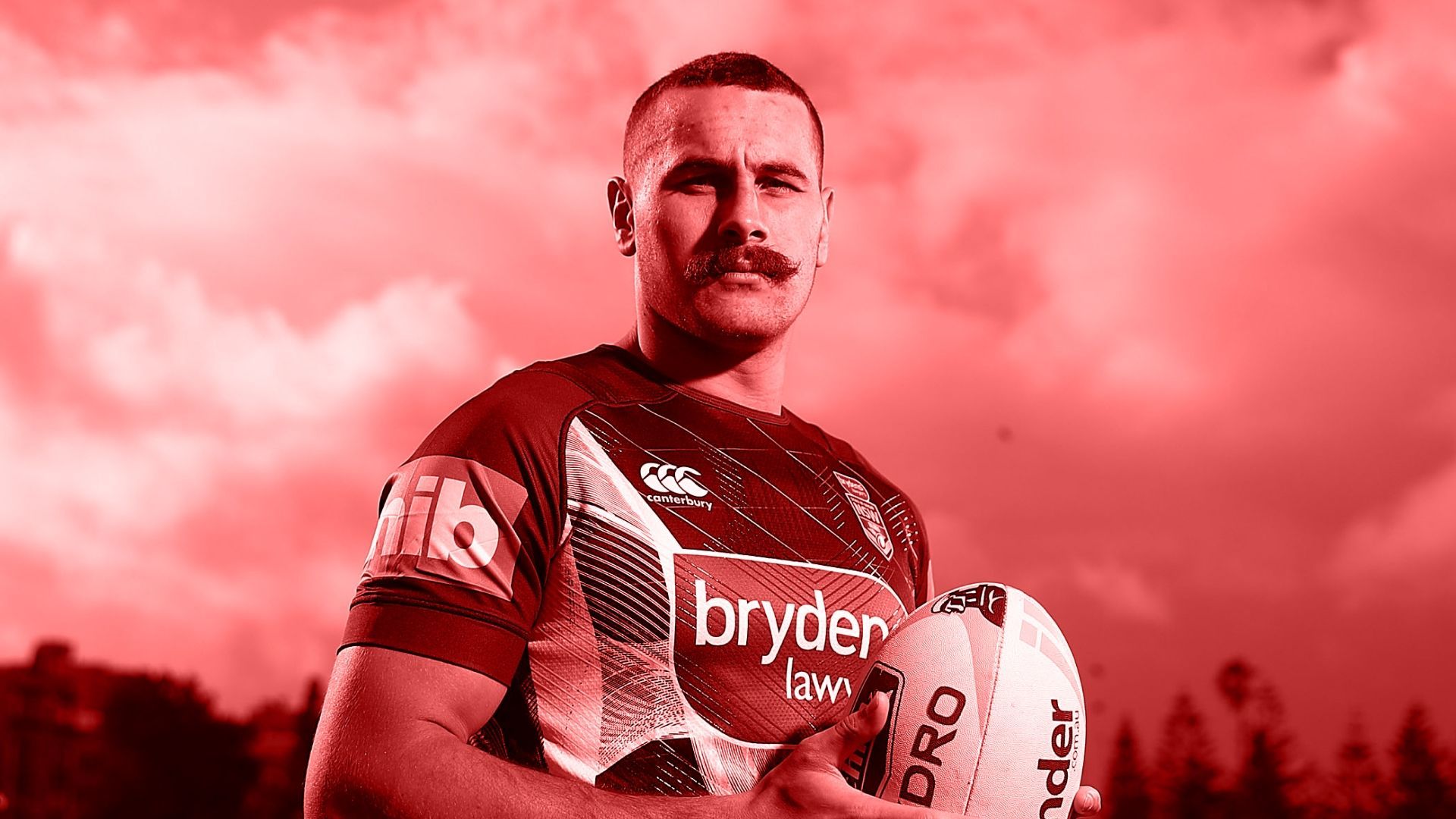 Rugby player holding a ball, red-tinted photo, outdoor setting.