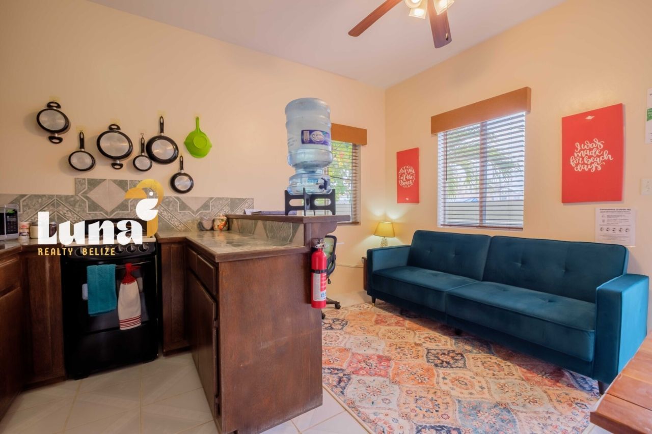 A living room with a couch , desk , lamp and window.