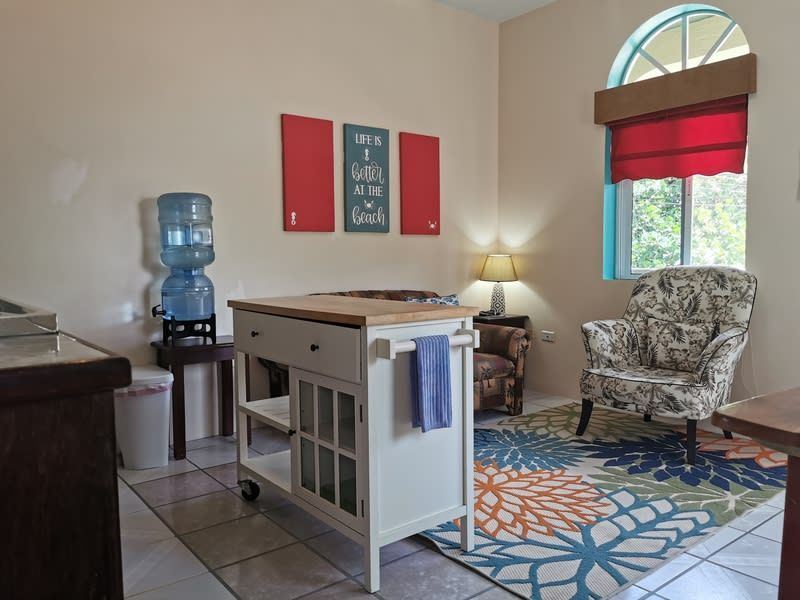 A living room with a chair , table , and a water cooler.