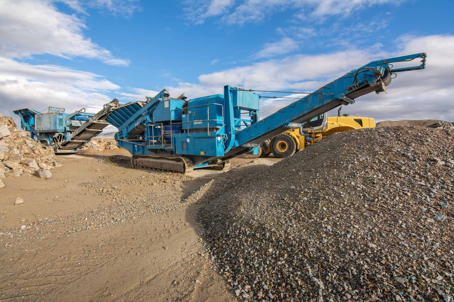 A blue machine is sitting on top of a pile of rocks.