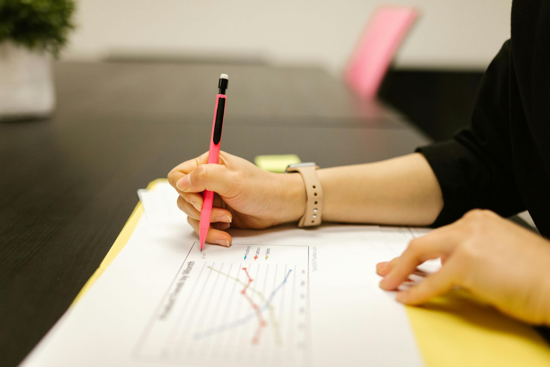 Hand writing on a chart with a red pencil at a WIlsona Marketing desk during a competitor analysis