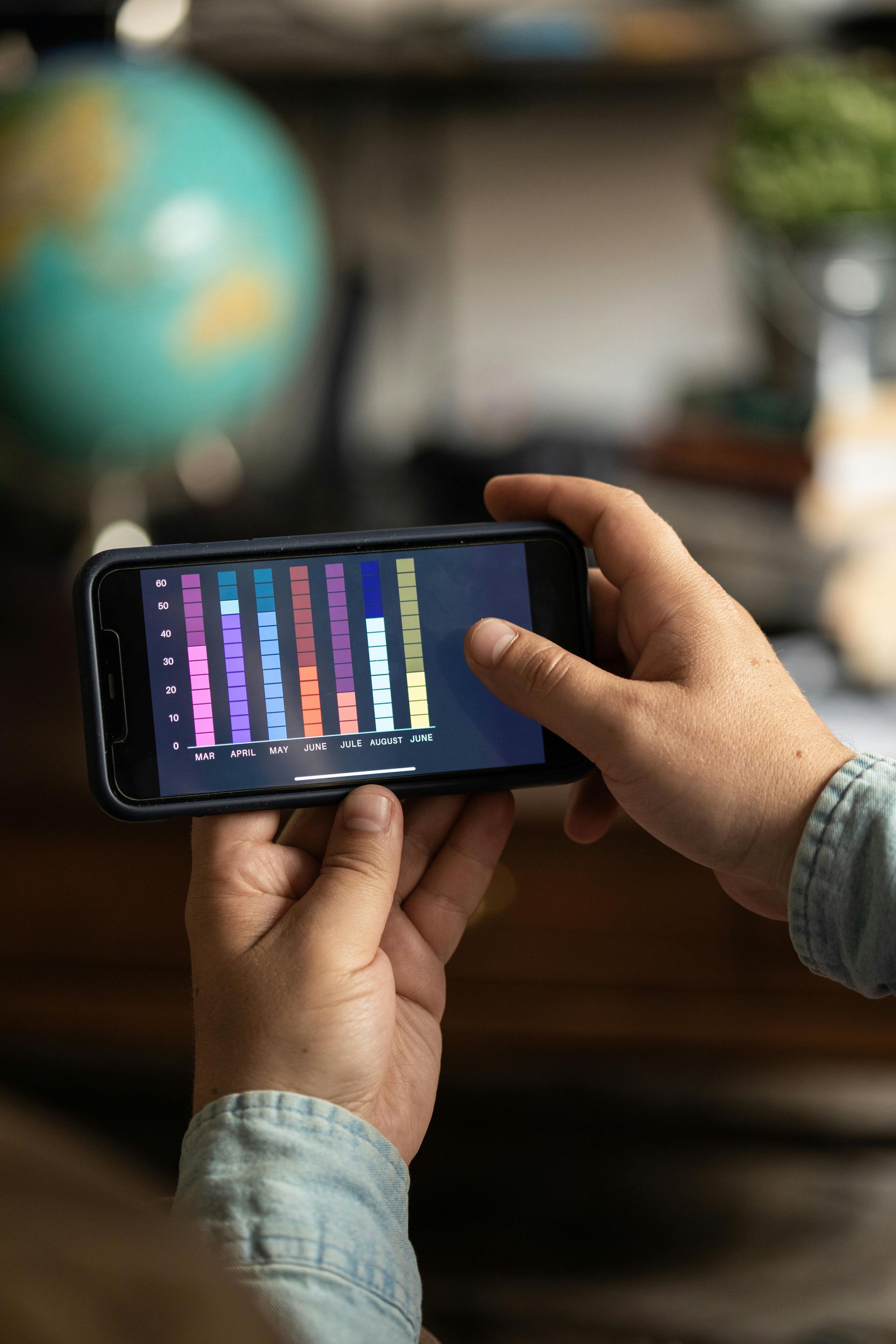 Hands holding a smartphone with a colorful graph on screen in a blurred indoor setting at Wilsona Marketing