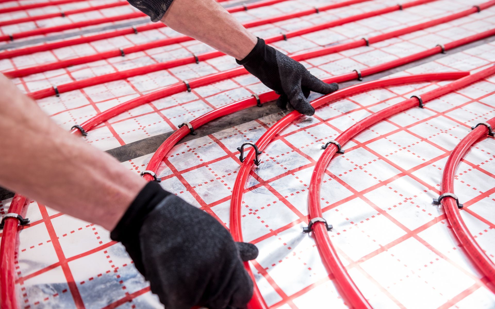 A man is installing underfloor heating pipes on the floor.
