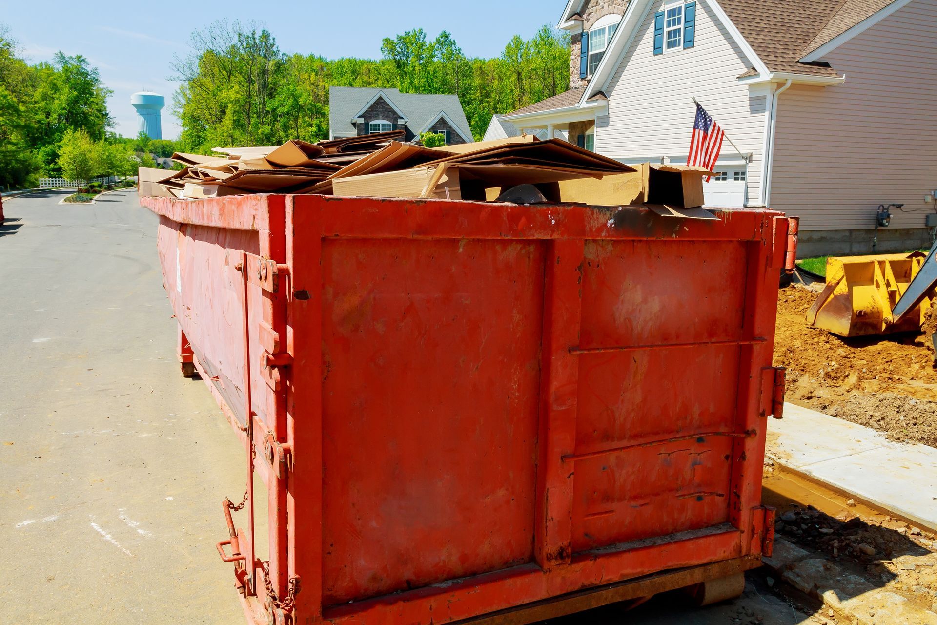 a red dumpster filled with wood is parked in front of a house .