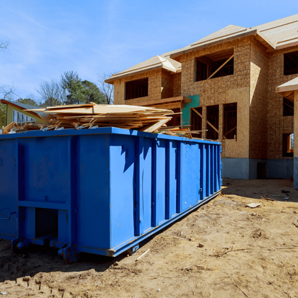 a blue dumpster is sitting in front of a house under construction