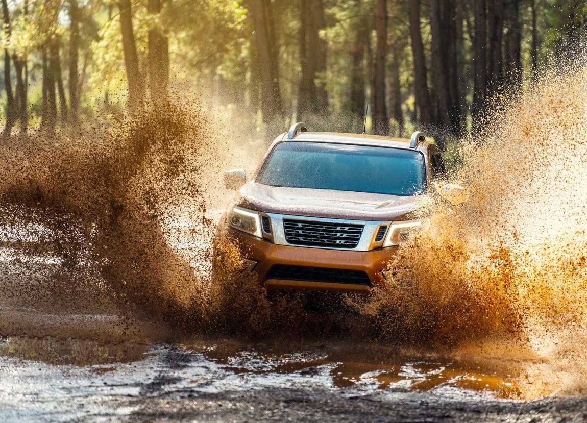 White SUV splashing through muddy water on a forest trail