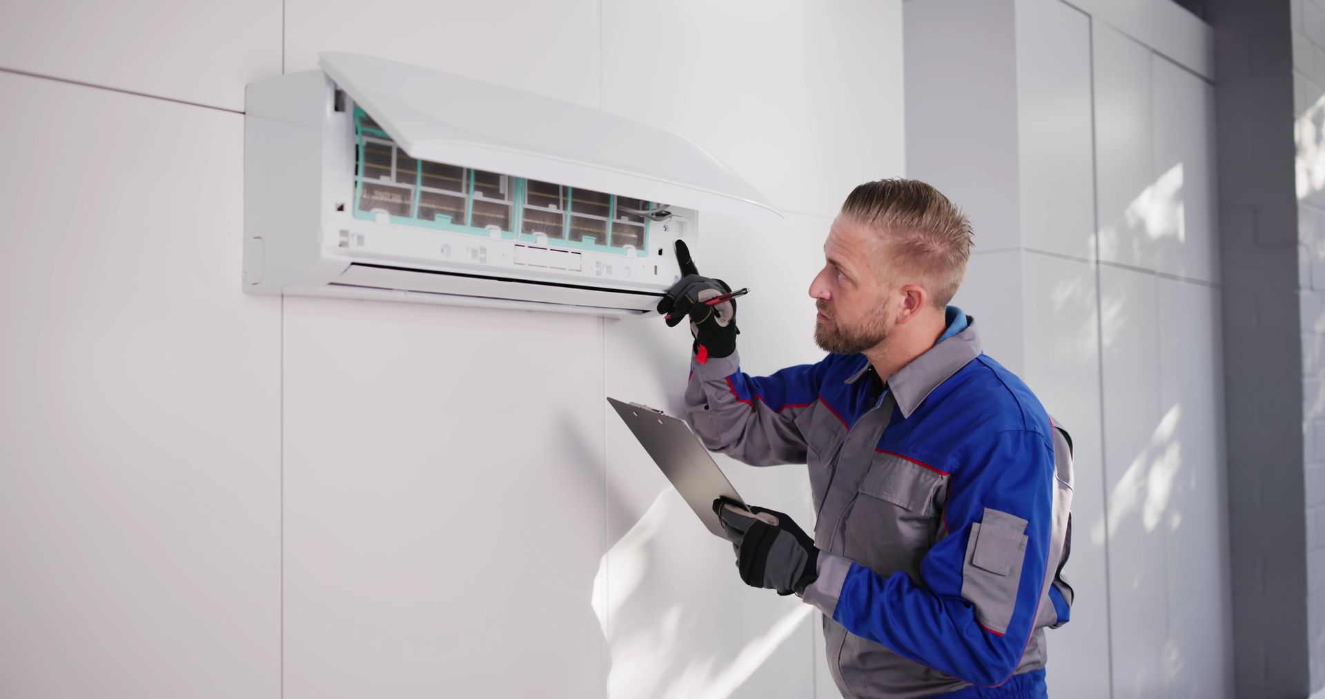 Technician inspecting a wall-mounted air conditioner with a clipboard in a bright room Technician inspecting a wall-mounted air conditioner with a clipboard in a bright room