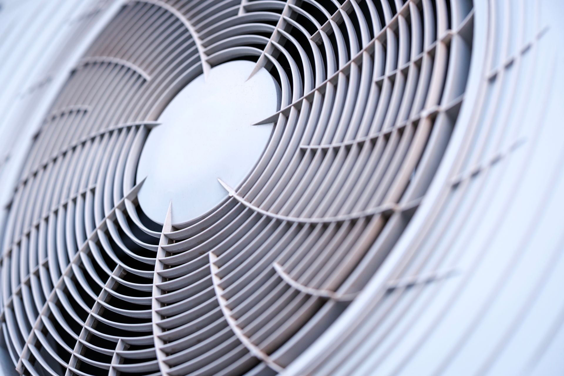 Close-up of a white industrial fan grille with curved blades behind it Close-up of a white industrial fan grille with curved blades behind it