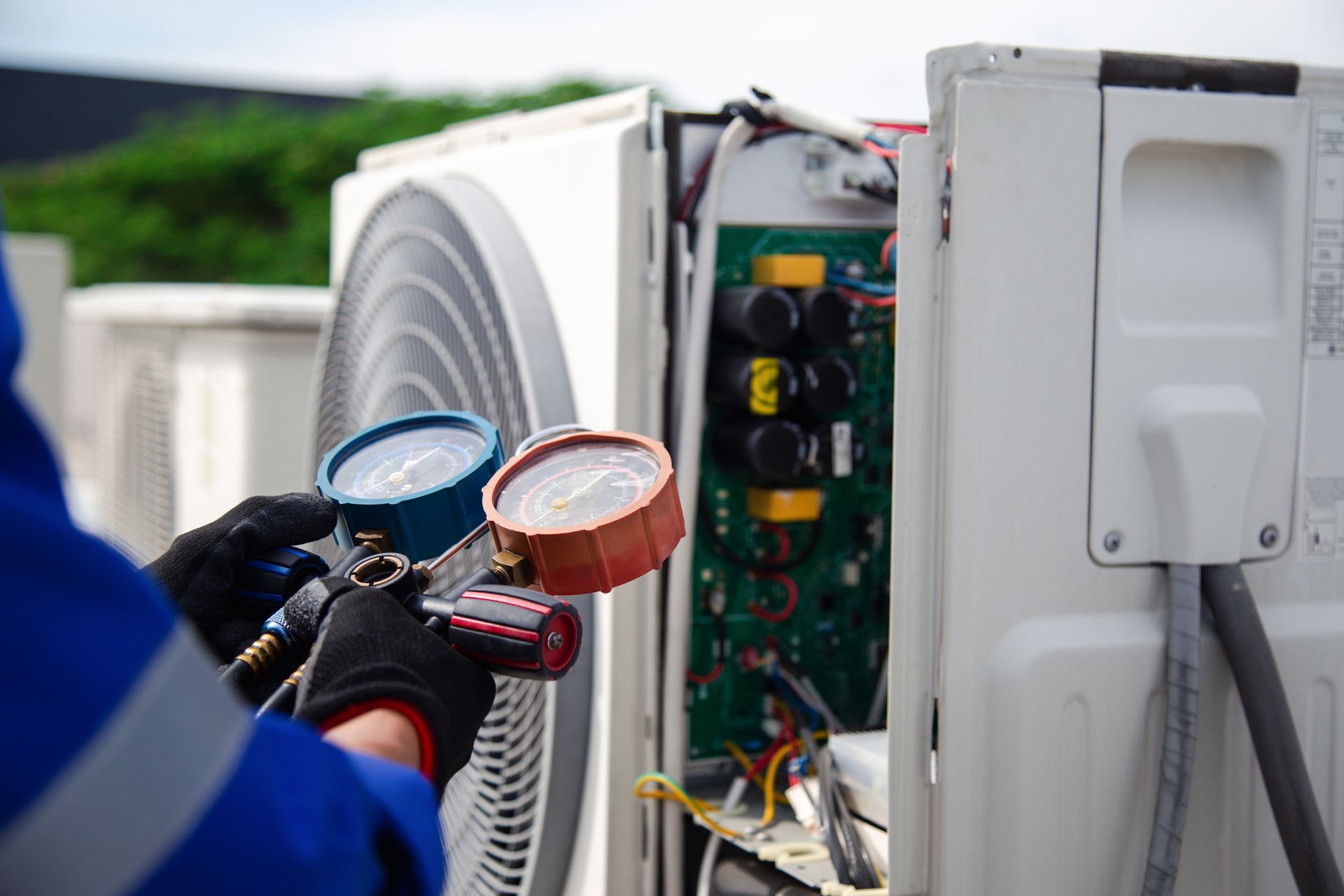 Technician checking outdoor HVAC unit with pressure gauges and exposed wiring Technician checking outdoor HVAC unit with pressure gauges and exposed wiring