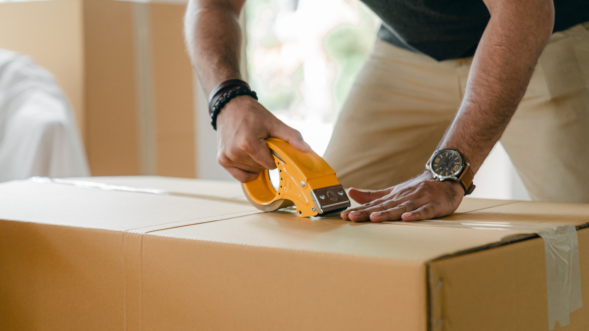 Person taping a cardboard box, close up view.
