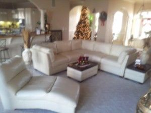 A living room with white furniture and a christmas tree in the background