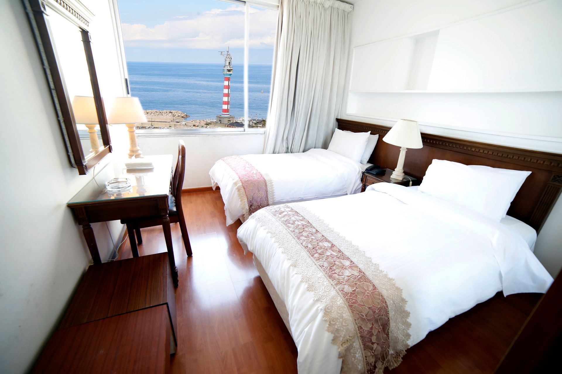 A hotel room with two beds and a lighthouse in the background
