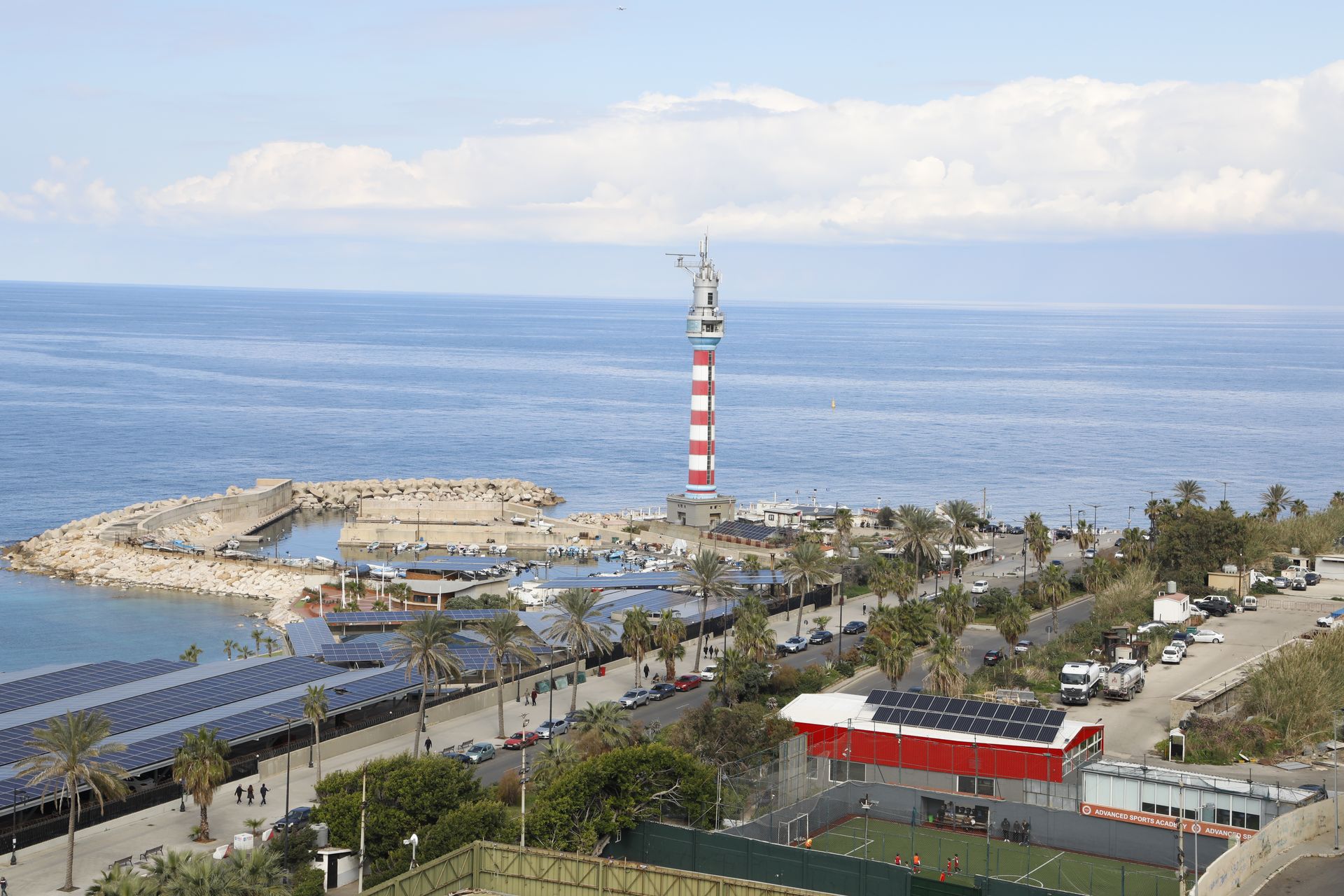 A red and white striped lighthouse is in the middle of the ocean