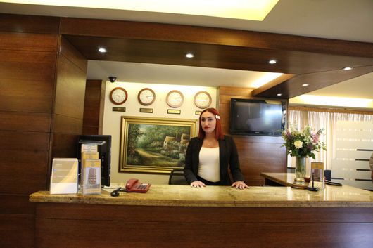 A woman stands behind a counter in a hotel lobby