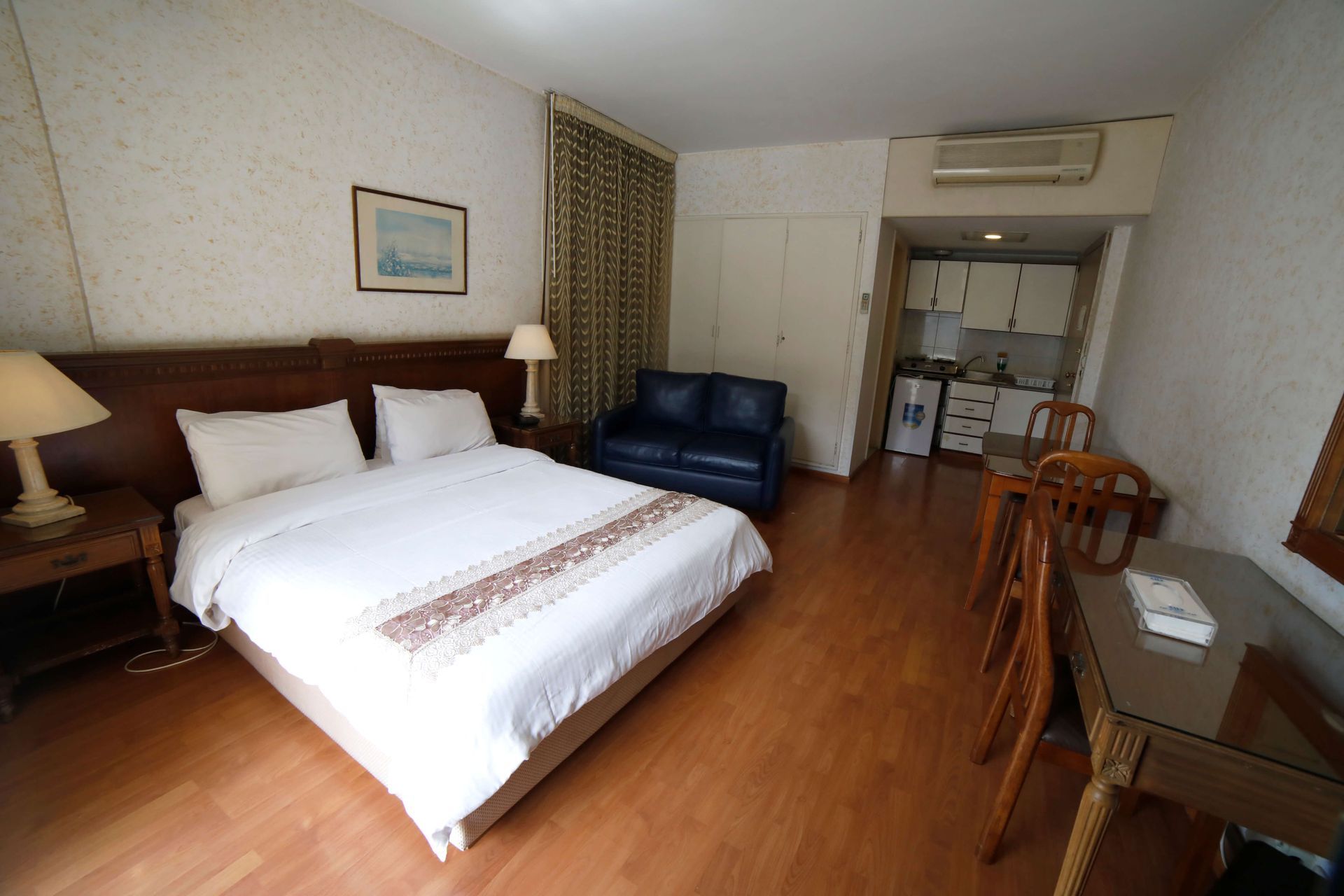 A hotel room with a king size bed and a blue couch