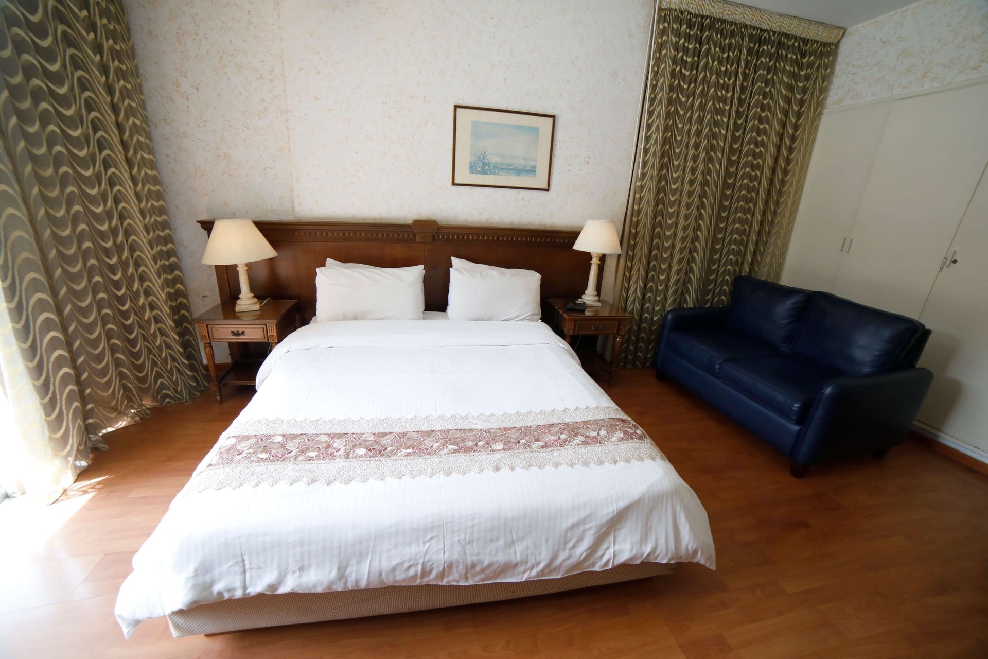 A hotel room with a large bed and a blue couch