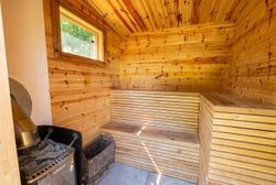 Wood-paneled sauna interior with bench seating, heater, and a small window