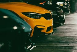 Yellow sports car parked beside other cars in a dimly lit parking lot