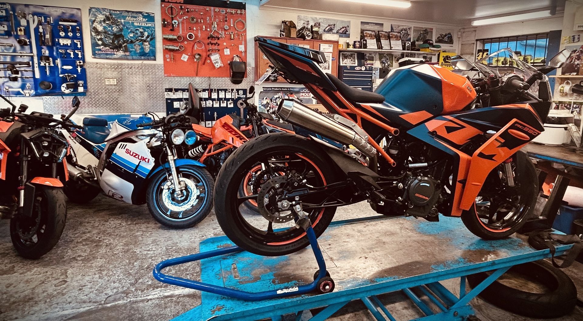 Orange and black sport motorcycle on a lift in a motorcycle shop, with other bikes in the background