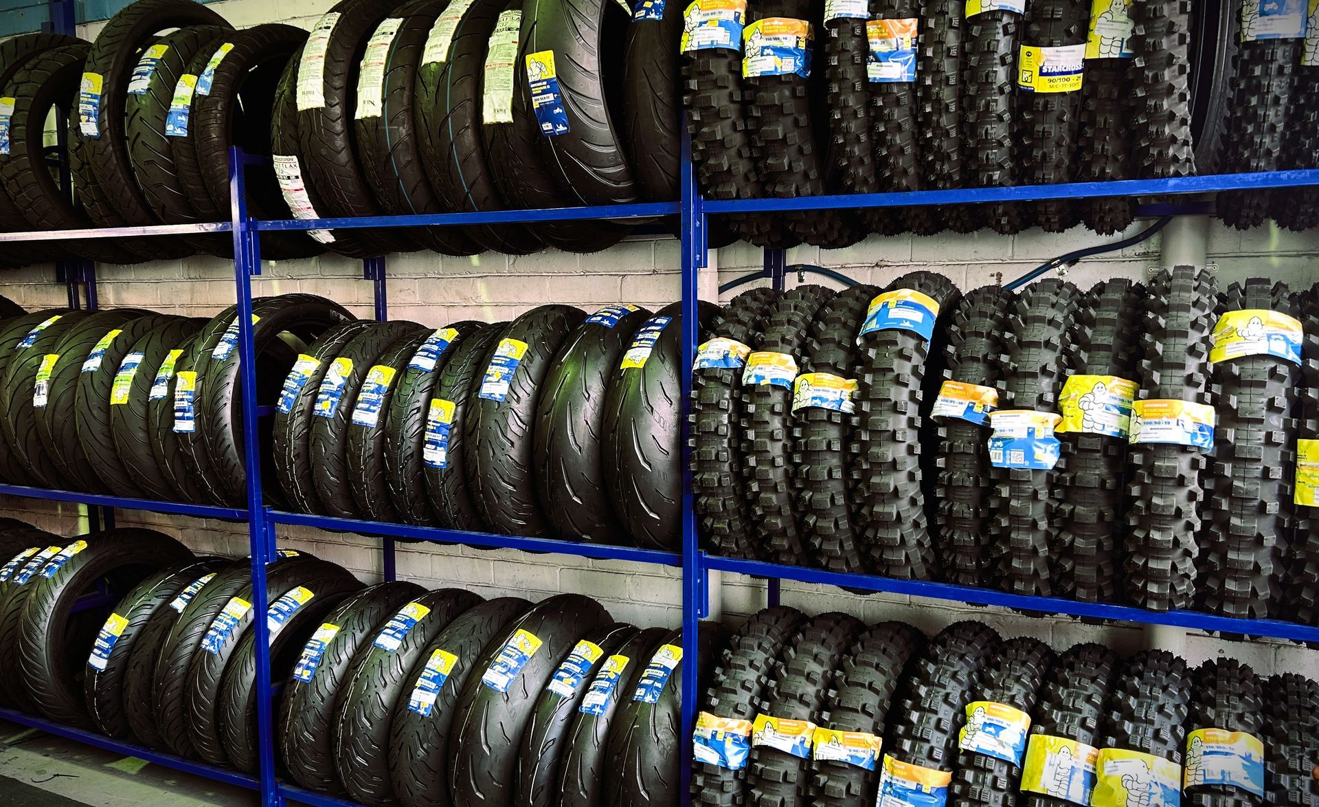 Stacks of black tires on metal shelves in a storage warehouse.