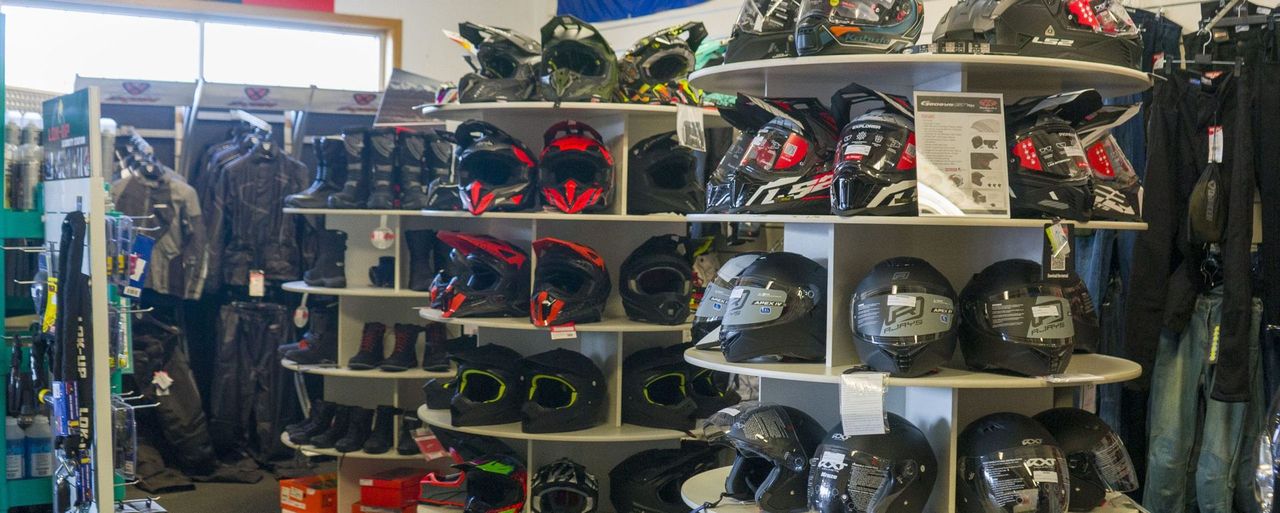 A retail store interior showing circular displays filled with various motorcycle helmets and riding boots on shelves.