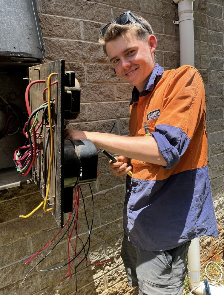 A Electrician Working on Wiring Box on a Brick Wall — McGrath Electrical & Data in South Grafton, NSW