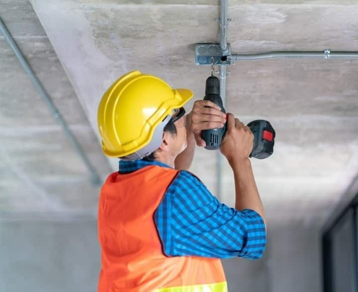 A Electrician in Yellow Hard Hat Installs Conduit on a Ceiling — McGrath Electrical & Data in South Grafton, NSW