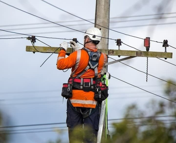 A Lineman in Orange Safety Gear Working on Power Lines on a Utility Pole — McGrath Electrical & Data in South Grafton, NSW