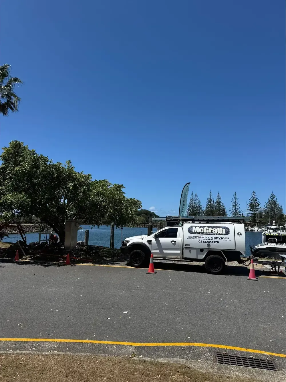 A McGrath Electrical ute is parked on the side of a road near a tree and ocean — McGrath Electrical & Data in South Grafton, NSW