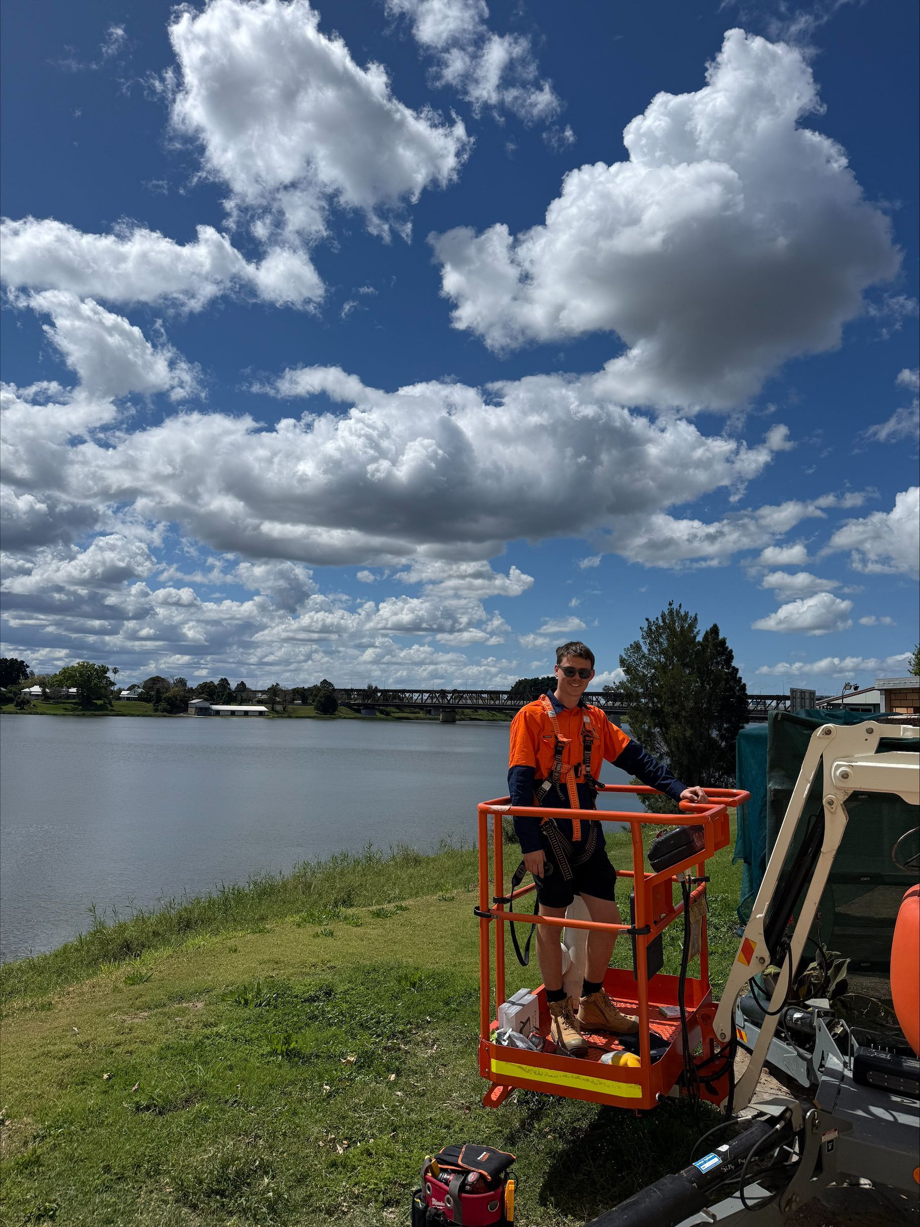 A employee is standing on a machine in an orange hi vis — McGrath Electrical & Data in South Grafton, NSW