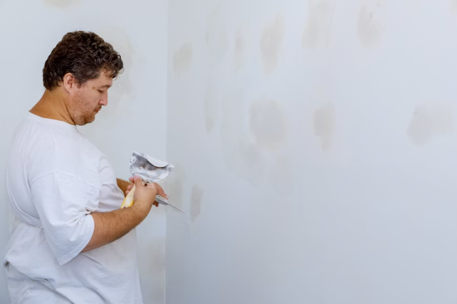 Worker applying joint compound to a drywall wall during installation by a drywall contractor in San Tan Valley, AZ