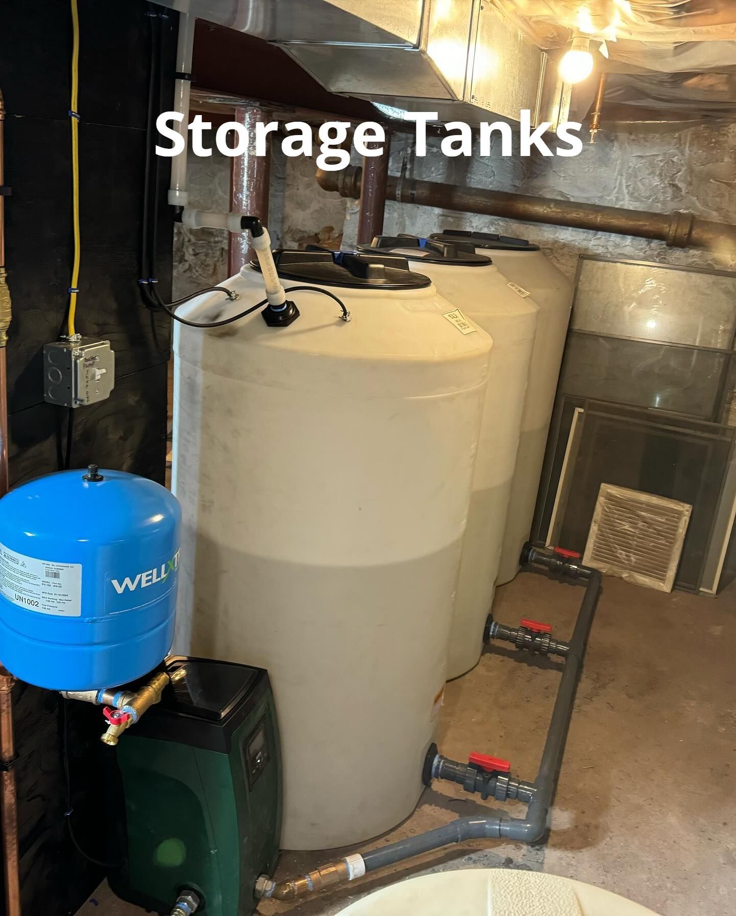 A row of storage tanks are sitting in a basement.