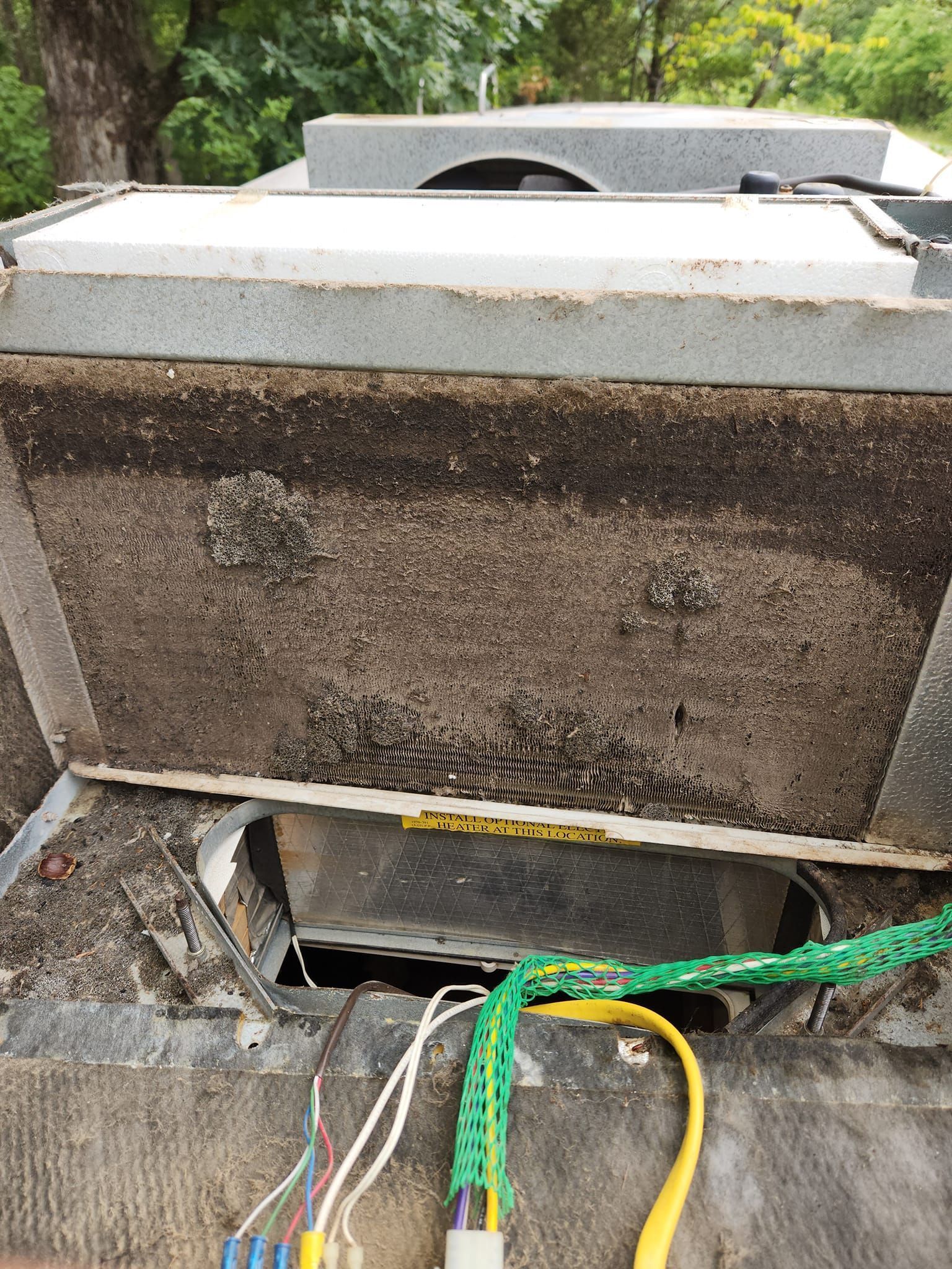 Open utility box with exposed cables and a rusted metal panel in an outdoor setting