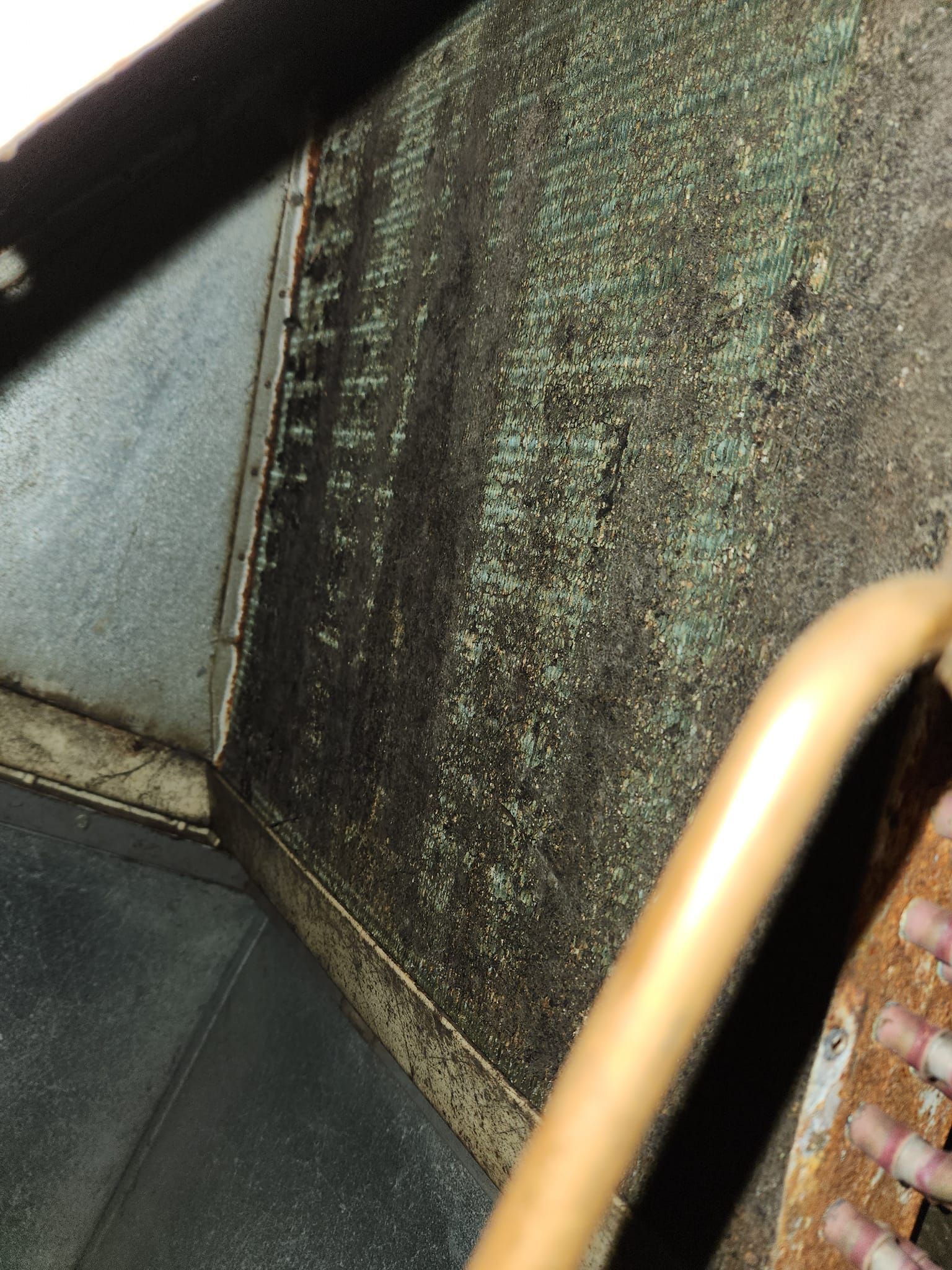 Close-up of a worn, textured seat back and metal handrail inside a vehicle or bus.