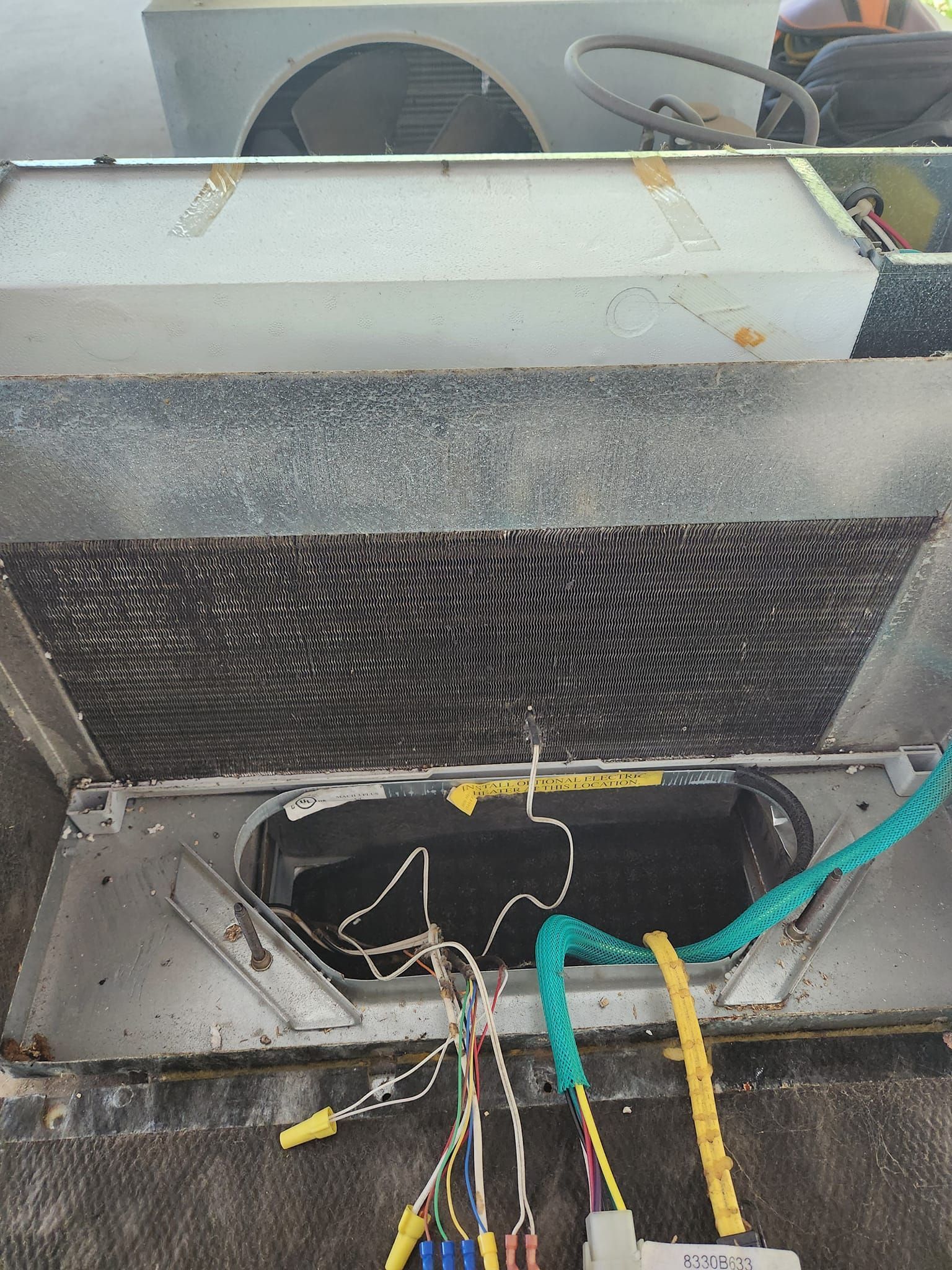 Open electrical panel with exposed wires and insulation inside a metal enclosure.