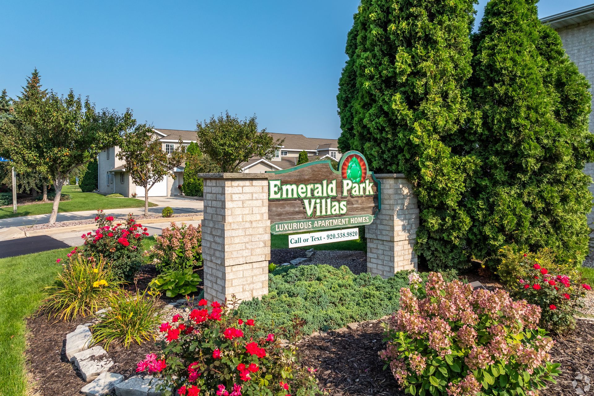 Entrance sign for Emerald Park Villas surrounded by landscaped flowers and trees