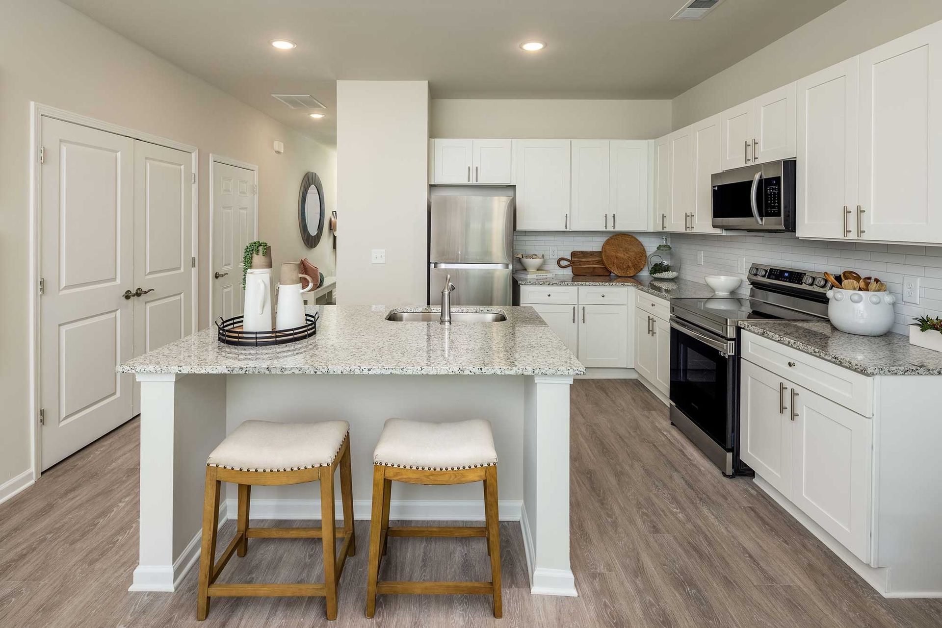 Bright modern kitchen with white cabinets, stainless appliances, and a marble island with two stools