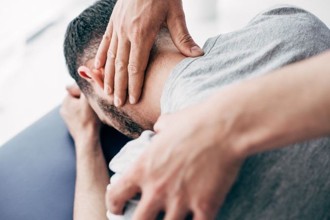 Person clutching their neck and shoulder in pain on a couch