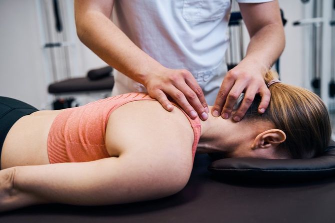 Massage therapist pressing shoulders of a woman lying face down on a massage table