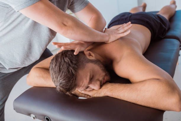 Massage therapist working on a man lying face down on a treatment table